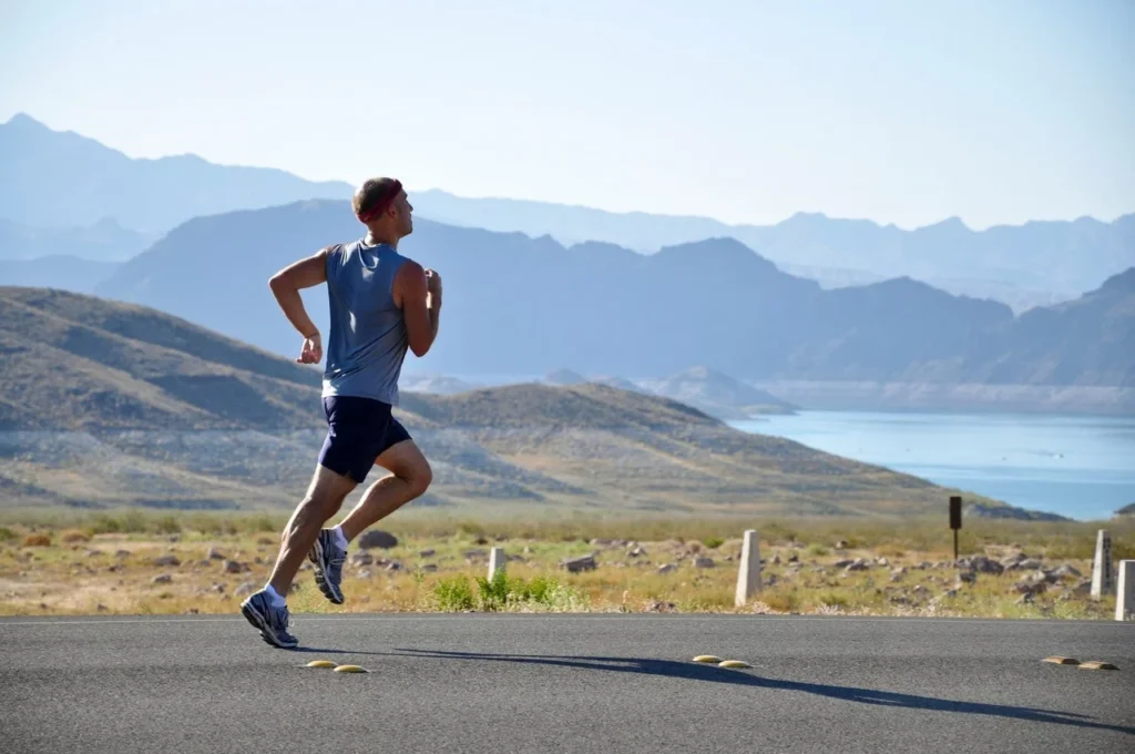 Man running on a road with a scenic mountain view during outdoor training